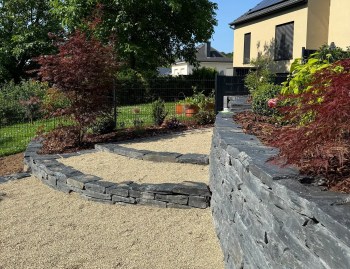 An exterior design for a detached house with sloping land: stone retaining walls.