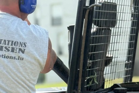 Un jardinier de Plantations Weisen passe la tondeuse dans le jardin d'un client au Luxembourg.