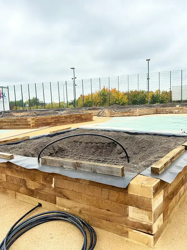 Il s'agit de billots de bois positionnés pour accueillir des plantations, dans une cour d'école au Luxembourg.